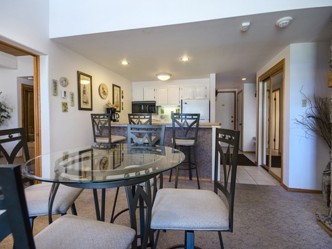 Enjoy your meals at the glass dining table or gather around the breakfast bar in this open-concept space, featuring a fully equipped kitchen ready for your culinary adventures.
