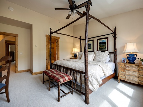 Step into your serene mountain bedroom featuring a handcrafted four-poster bed, where vaulted ceilings and rustic elegance invite you to unwind completely.