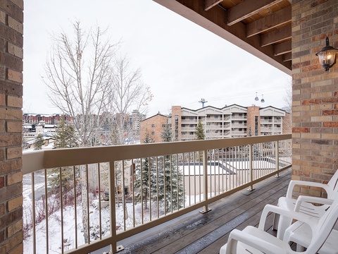 A covered balcony with mountain resort views, where you can relax in your private chair and watch the seasons change across the snow-dusted evergreens and surrounding village.