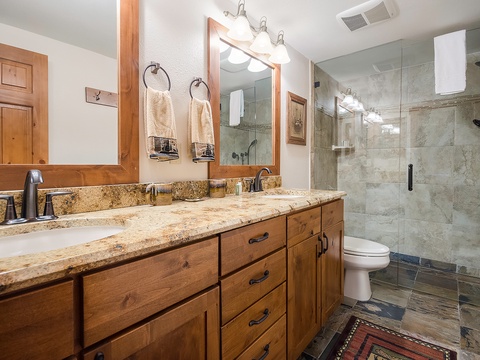 Step into your beautifully designed bathroom, where warm wood cabinetry meets elegant granite countertops. Enjoy the spacious walk-in shower and dual vanity setup for ultimate comfort.
