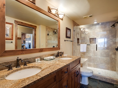 Step into your beautifully appointed bathroom with warm wood tones, granite dual vanities, and a luxurious walk-in shower designed for ultimate relaxation and comfort.