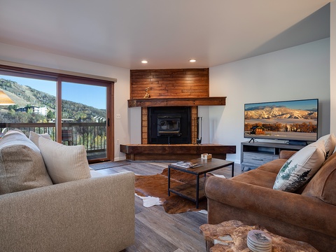 Relax by the fireplace and mountain views in your cozy living room. Plush seating, warm wood accents, and a modern TV await.