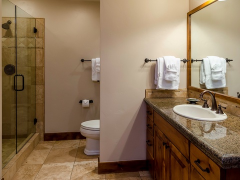 Your private bathroom features a granite vanity, glass-enclosed shower, and fresh towels—everything you need to unwind after a day of exploring nearby attractions.