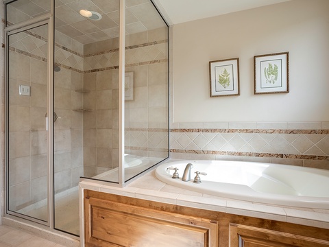 Unwind in your private spa-like retreat featuring a deep soaking tub and spacious walk-in shower with elegant tile work and natural light.