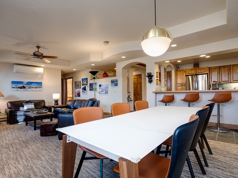 Gather your group around this spacious open-concept living and dining area. Rich wood cabinets, modern bar seating, and a stylish dining table create the perfect setting for shared meals and memorable moments together.