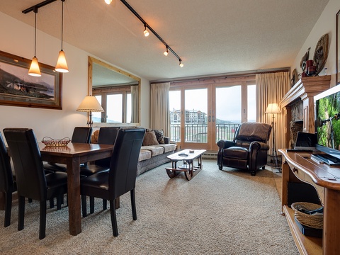 Step into your inviting open-concept space where warm wood tones and comfortable furnishings create the perfect setting for memorable moments, all framed by stunning waterfront views through expansive windows.