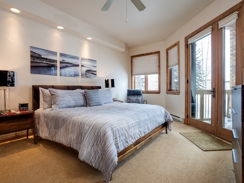 Wake to natural light streaming through your private balcony doors in this serene bedroom, where plush bedding and mountain-modern décor invite you to unwind completely after a day exploring.