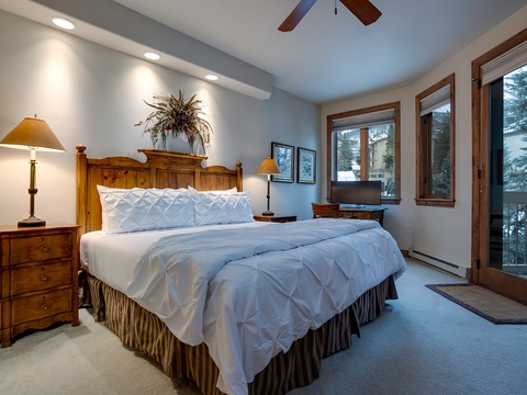 Step into your cozy bedroom retreat, where plush white bedding invites restful sleep. Warm wood furnishings and mountain views through large windows create a peaceful alpine escape.