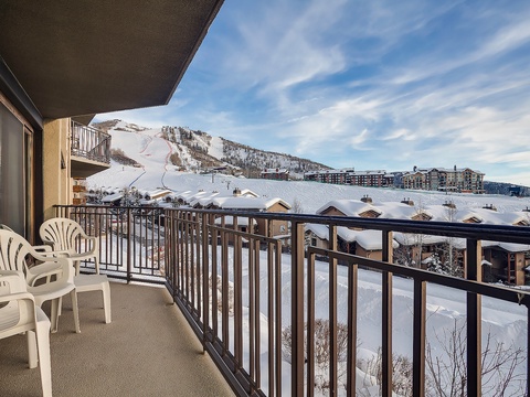 A private balcony overlooks snow-covered slopes and a vibrant ski village below, offering breathtaking alpine views for your mountain getaway.