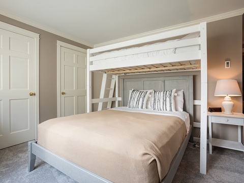 Your stylish bedroom blends comfort with clever design, featuring a bunk bed above a plush queen bed—perfect for families or extra guests while maintaining a serene, inviting ambiance.