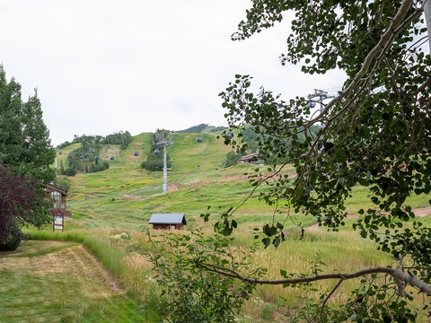 Mountain property nestled among aspens and rolling hills, with ski lift visible in the distance—a peaceful setting for all seasons.