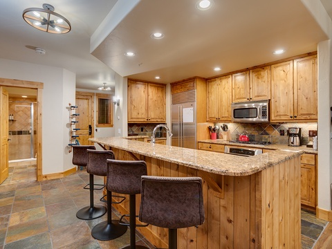 Your fully equipped kitchen features granite countertops, stainless steel appliances, and a spacious island with seating—perfect for preparing meals and gathering together during your mountain getaway.