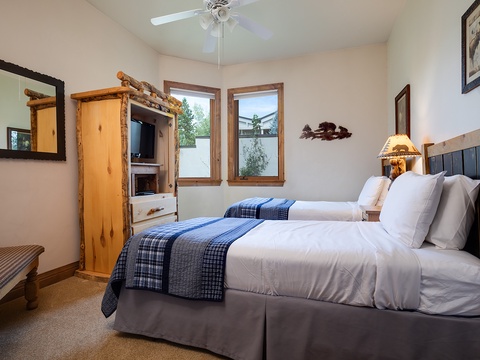 Settle into your cozy retreat with plaid-accented twin beds, rustic mountain decor, and a peaceful view. Your private space awaits with thoughtful touches like a ceiling fan and charming pine furnishings.