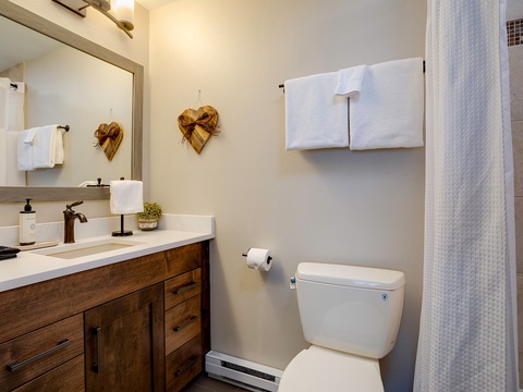 Step into your private bathroom, where rustic charm meets modern comfort. Fresh towels await, and the warm wood vanity and heart-shaped accents create a cozy, welcoming atmosphere for your stay.