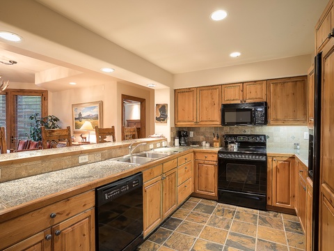 Your fully equipped kitchen with granite countertops, modern appliances, and ample cabinet space makes preparing meals a breeze. Warm wood tones and thoughtful lighting create a welcoming space for your mountain getaway.