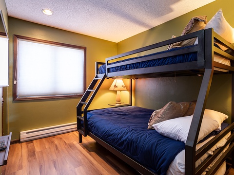 Your cozy bunk room glows with warm golden walls and offers comfy layered bedding—perfect for kids or groups. Natural light fills the space, making it feel like home.