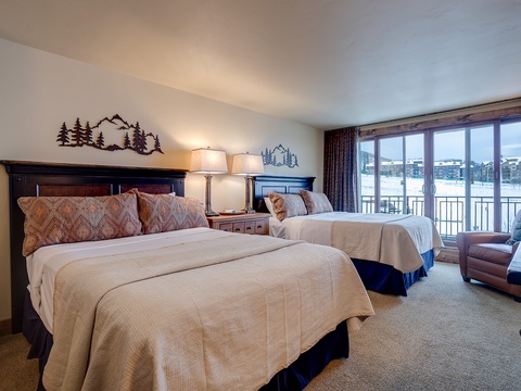 Wake up to serene winter views in this inviting bedroom with two plush beds, cozy mountain-inspired décor, and a private balcony overlooking snowy landscapes.