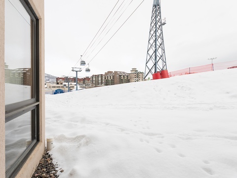Ski resort location features direct access to slopes with gondola lifts and nearby alpine village buildings, surrounded by pristine winter snow.