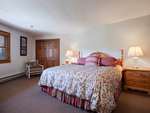 Sink into comfort in your private bedroom, where warm wood accents and soft, colorful linens create a cozy retreat after a day of mountain adventures.