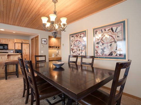 Step into your vacation dining space, where a warm wood ceiling and elegant chandelier create the perfect setting for shared meals and mountain memories around this spacious table.