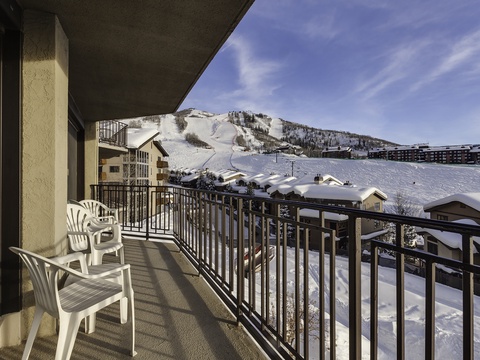 This property is located in a winter resort area with direct views of ski slopes and surrounding snow-covered buildings. The balcony provides a panoramic mountain setting.