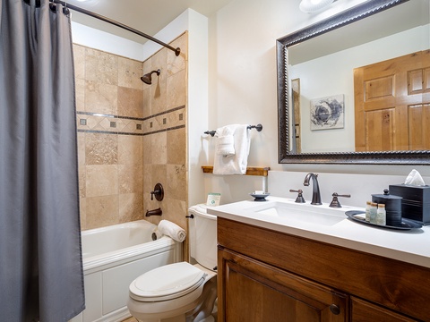 Step into your beautifully appointed bathroom, where warm travertine tile and elegant wood vanity create a spa-like retreat. Enjoy a refreshing shower before your next mountain adventure.