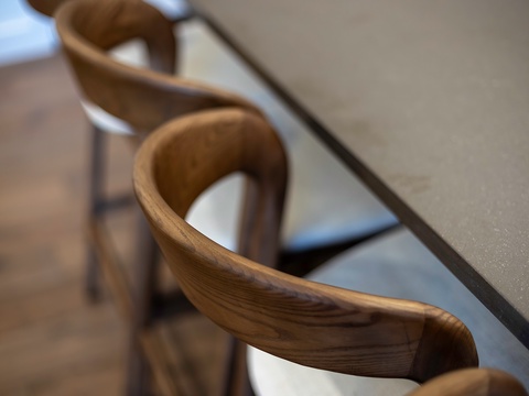 Sculptural wooden chairs with flowing lines invite you to gather around the sleek counter for meals or conversation in this thoughtfully designed space.