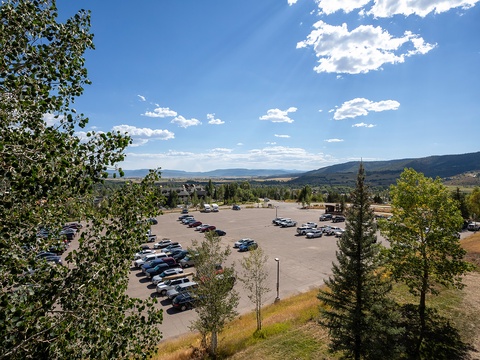 Spacious parking lot with ample vehicle storage, framed by lush greenery and sweeping mountain vistas under bright blue skies.
