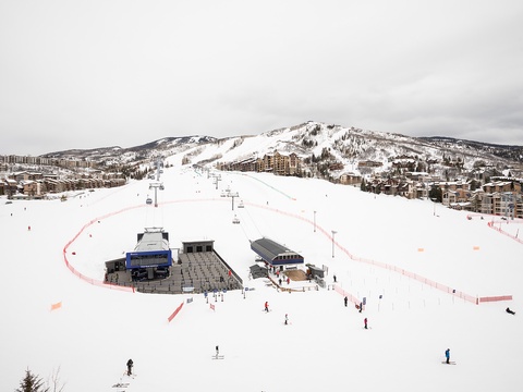 Expansive ski terrain with groomed runs, chairlifts, and base lodges nestled at the foot of snow-covered slopes, surrounded by mountain village accommodations.
