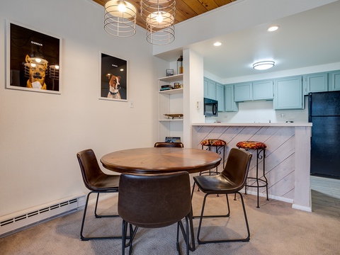 Gather at your own stylish dining table beneath warm pendant lights, with a fully-equipped kitchen featuring soft blue cabinetry just steps away.