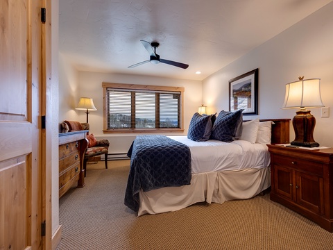 Your peaceful retreat features a plush bed dressed in soft linens, warm lighting, and mountain views through the window. Sink into comfort after a day of adventure.