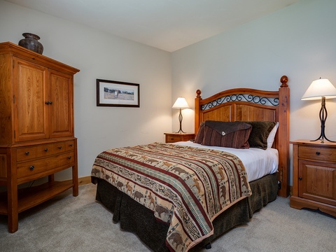Sink into the plush bed dressed in rustic textiles and flanked by warm lamps—your peaceful retreat awaits with handcrafted wood furnishings and mountain charm inviting total relaxation.