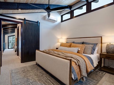 Your modern mountain retreat features soaring ceilings, a plush king bed dressed in luxe linens, and a striking barn door that adds rustic charm to this airy, light-filled sanctuary.