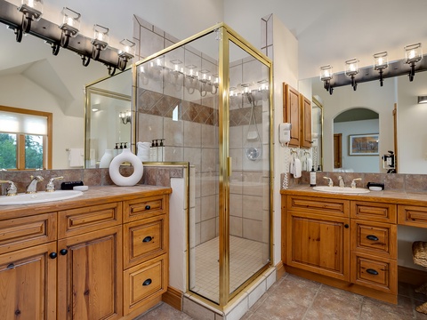 Step into your private spa-like retreat with dual vanities, elegant tilework, and a spacious glass-enclosed shower. Warm wood cabinetry and designer lighting create a luxurious haven for your morning and evening routines.