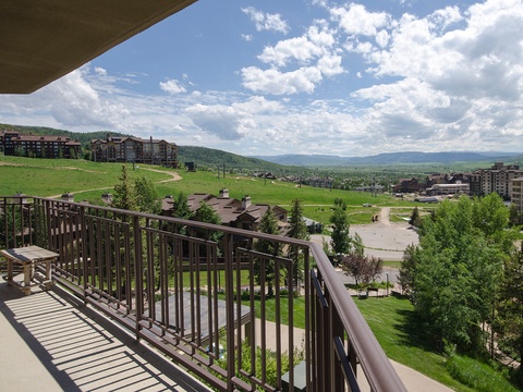 Expansive mountain resort area featuring green hillsides, scattered residential buildings, and a dramatic sky—part of the surrounding neighborhood near the property entrance.