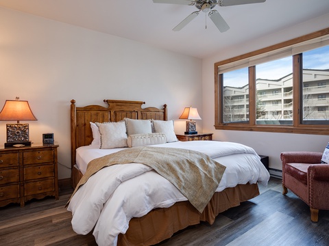Sink into crisp white linens on your plush bed, warmed by soft lamplight and cooled by the ceiling fan above. Wake up to nearby mountain views through large windows in this cozy, inviting retreat.