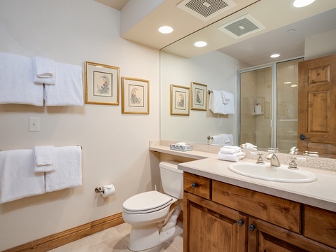 Step into your well-appointed bathroom, where warm wood cabinetry and plush towels await. Enjoy fresh linens, thoughtful artwork, and modern fixtures that make refreshing effortless.