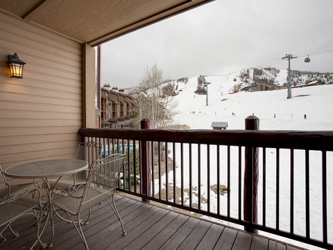Private balcony overlooking snowy ski slopes with gondola lifts and mountain views, complete with outdoor seating for your morning coffee.