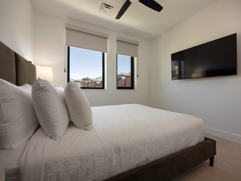 Drift off in this serene bedroom with crisp white linens and natural light streaming in. Your ceiling fan keeps the space cool, while a wall-mounted TV provides evening entertainment.