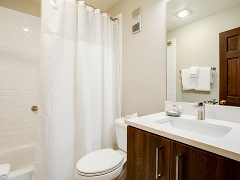 Refresh in your private bathroom with crisp white tile, modern vanity with generous counter space, and fresh fluffy towels waiting for your arrival.