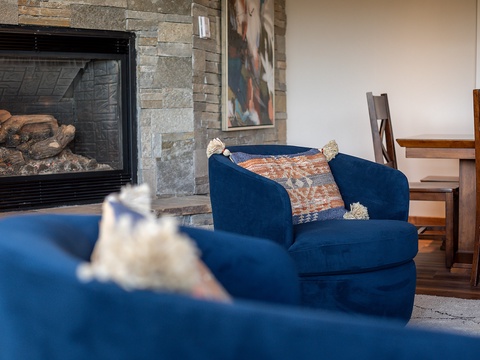 Settle into plush armchairs by the stone fireplace, where warmth and style create your perfect retreat for cozy evenings and mountain conversations.