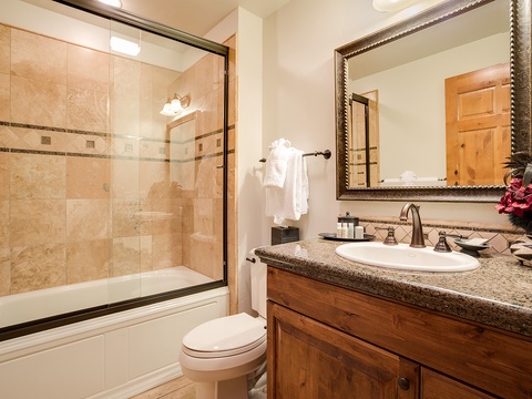 Your private bathroom features warm tiled finishes, a spacious tub-shower combo, and thoughtful touches like fresh towels and elegant fixtures for your comfort.