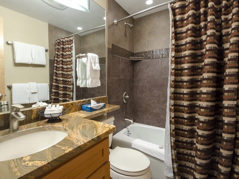 Step into your stylish bathroom with warm granite countertops, sleek tiled shower-tub, plush towels, and thoughtful touches that make freshening up feel like a retreat.