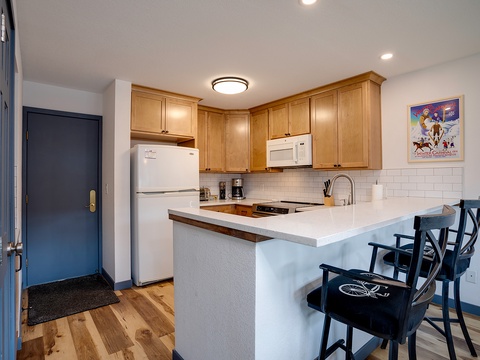 Step into your fully equipped kitchen with warm wood cabinetry, modern appliances, and a breakfast bar perfect for morning coffee or casual meals with loved ones.