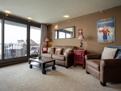 Unwind in your cozy living room with warm leather sofas and vintage Colorado charm, where expansive windows frame Steamboat's mountain views.