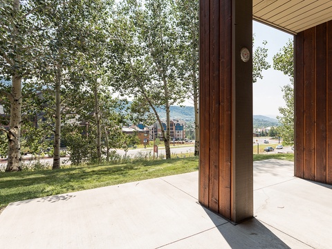 Property entrance features a covered walkway overlooking nearby buildings, green spaces, and mountain views in the surrounding resort area.