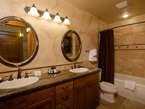 Your private bathroom features elegant dual vanities, a soaking tub, and warm travertine tile throughout—perfect for unwinding after a day of mountain adventures.