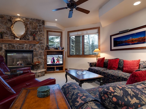 Settle into your cozy living room with a crackling stone fireplace, plush seating, and mountain artwork that captures the alpine spirit all around you.