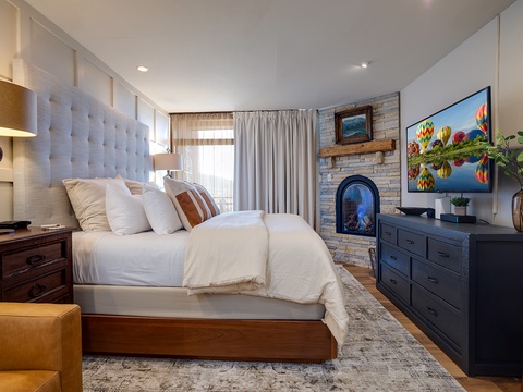 Sink into plush comfort beneath a statement headboard. Your room features a cozy fireplace, modern entertainment, and warm wood finishes for a truly restful retreat.