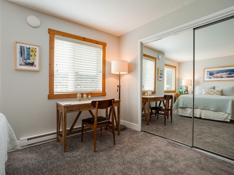 Your peaceful retreat features a cozy workspace by the window and mirrored closets that open up the space, creating an airy feel perfect for unwinding after your adventures.